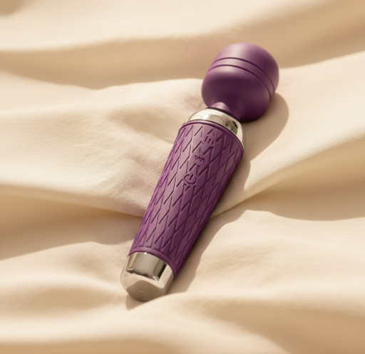 Purple handheld wellness massager resting on soft beige fabric in warm natural light